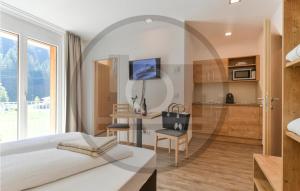 1 dormitorio con cama, escritorio y cocina en Amazing Apartment In Klsterle With Kitchenette, en Klösterle am Arlberg