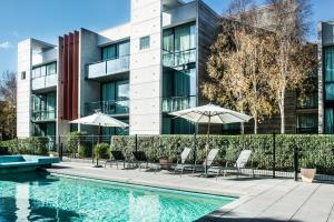 a swimming pool with chairs and umbrellas in front of a building at Phillip Island Apartments in Cowes