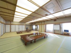 Hiroshima International Youth House JMS Aster Plaza في هيروشيما: غرفة كبيرة بها طاولات وكراسي