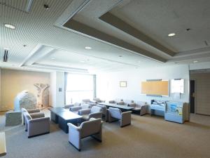 a waiting room with chairs and tables and a screen at Hiroshima International Youth House JMS Aster Plaza in Hiroshima