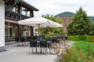 un patio con mesas, sillas y una sombrilla en Hotel Müllerhof en Frick