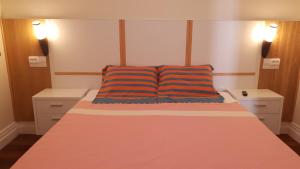 a bedroom with a bed with a orange and blue pillow at BRUMA HOSTEL in Ponta Delgada