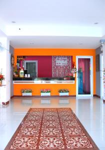 a lobby with an orange wall and a large rug at The Cottage Lampang in Lampang