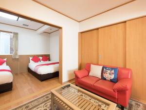 a living room with a red couch and a bed at Tama Hotel in Ishinomaki
