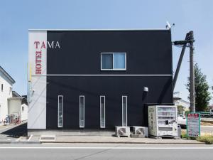 un bâtiment noir avec un panneau sur son côté dans l'établissement Tama Hotel, à Ishinomaki