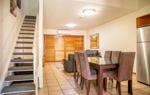a dining room with a table and chairs and a staircase at Presidential Bungalow in Busselton