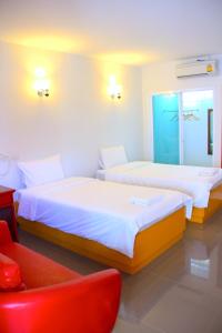 two beds in a room with a red chair at The Cottage Lampang in Lampang