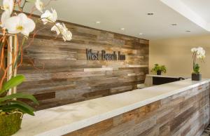 a lobby with a wooden wall with the words guest arousal inn at West Beach Inn, a Coast Hotel in Santa Barbara