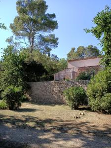 a brick retaining wall with a tree and a building at Grande Maison Mitoyenne & Spa à Bulles au Soleil dans Quartier Calme ! in Entrecasteaux