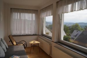 um quarto com duas janelas, uma cadeira e uma mesa em Ferienhaus Weitblick em Bad Pyrmont