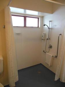 ein Bad mit einer Dusche, einem WC und einem Fenster in der Unterkunft Valdez Motor Lodge in Hastings