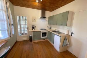 una cucina con armadi verdi e pavimenti in legno di Gite Jeanroy a Cheerful 2 Bedroom Rural Gite a Saint-Martial-Viveyrol