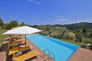 einen Pool mit Stühlen und einem Sonnenschirm in der Unterkunft Casale Vittoria in Marti