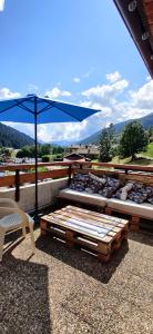 a patio with three beds and a blue umbrella at Le Rookie Mountain in Le Grand-Bornand
