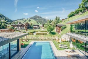 uma vista para uma casa com piscina e montanhas em Rosentalerhof Hotel & Appartements em Saalbach-Hinterglemm