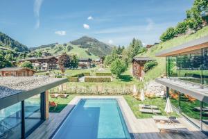 Blick auf ein Haus mit Pool und Berge in der Unterkunft Rosentalerhof Hotel & Appartements in Saalbach-Hinterglemm