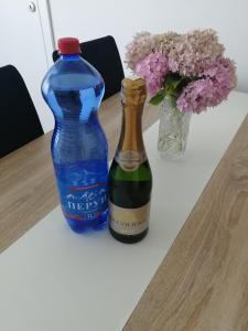 Una botella de vino azul junto a un jarrón de flores. en Family hоuse en Banja Koviljača