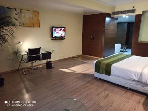 a hotel room with a bed and a desk and a tv at Hotel Patliputra Exotica in Patna