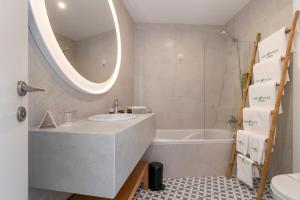 a bathroom with a sink and a tub and a mirror at Aqua Natura Bay in Porto Moniz