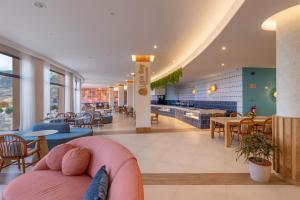 a lobby with a pink couch and tables and chairs at Aqua Natura Bay in Porto Moniz