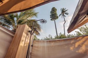 a view of a fence with palm trees in the background at Khwan Beach Resort - Luxury Glamping and Pool Villas Samui - Adults Only - SHA Extra Plus in Mae Nam