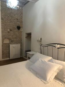 a bedroom with a white bed and a stone wall at B&B Le Principesse in Sermoneta