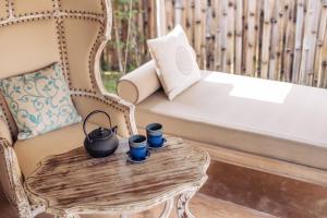 a chair and a table with two cups on it at Khwan Beach Resort - Luxury Glamping and Pool Villas Samui - Adults Only - SHA Extra Plus in Mae Nam
