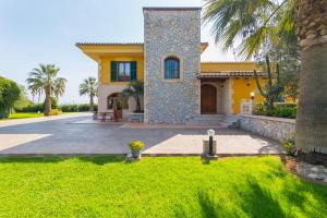 ein gelbes Haus mit einer Palme und einer Auffahrt in der Unterkunft Can Marti Bea in Sa Pobla