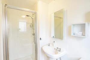 a white bathroom with a sink and a shower at Heather Lodge 4, sleeping 6 in Belladrum