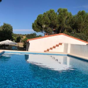 a large swimming pool with blue water and stairs at Casa en Finca, Villa con Piscina Zarzuela in Villaviciosa de Odón