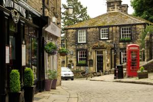 an old building with a red phone booth on a street at Haworth Home - Hot tub Cinema Games Room Sleeps 12 in Haworth