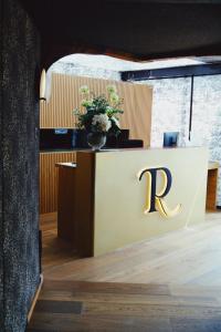 a reception desk with a letter r on it at Hôtel Restaurant Relais De La Poste - Strasbourg Nord in La Wantzenau