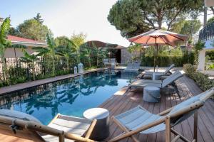 a swimming pool with lounge chairs and an umbrella at CUNDA PİER OTEL in Ayvalık