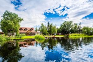 a view of a lake with a house in the background at Dolina Biebrzy - Ośrodek Agroturystyczny in Wroceń