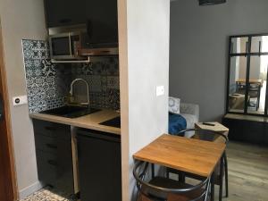uma pequena cozinha com um lavatório e uma mesa em Le Florence em Saint-Quentin