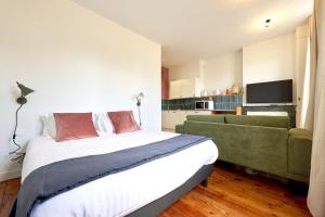 a bedroom with a bed and a green couch at Le Nid - appartements Bordeaux Centre in Bordeaux