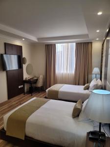 Cette chambre comprend deux lits et un bureau. dans l'établissement Goha Addis Hotel, à Addis-Abeba