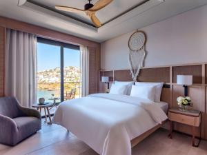 a bedroom with a large bed and a large window at MGallery The Bodrum Hotel Yalikavak in Yalıkavak