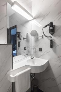 Baño blanco con lavabo y espejo en Hotel Belmont Classic en Bonn