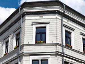 a white building with windows and flowers on it at Amber in Liepāja