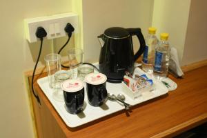 a tray with a coffee pot and glasses on a counter at Hotel Grand Kailash,Kotdwara in Kotdwāra