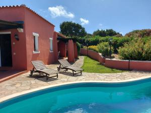 a house with two chairs next to a swimming pool at Villa Venere in Stintino
