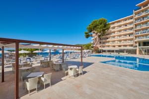 a hotel patio with tables and chairs next to a swimming pool at Grupotel Playa Camp de Mar - Adults Only in Camp de Mar