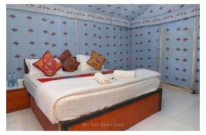 um quarto com uma cama com almofadas em Shiv Tara Desert Camp em Sām