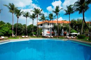 a swimming pool in front of a hotel with palm trees at Trident Chennai in Chennai