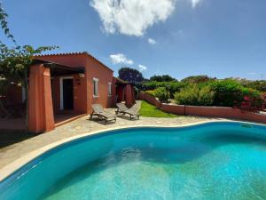 a swimming pool with two chairs and a house at Villa Venere in Stintino