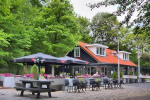 een restaurant met tafels, stoelen en parasols bij Apartments Valkenisse in Biggekerke