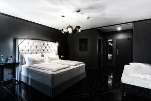 a black bedroom with a large bed with white sheets at Hotel Belmont Classic in Bonn