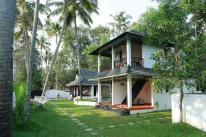 a house in the middle of a yard with palm trees at Mayas Beach House in Mararikulam