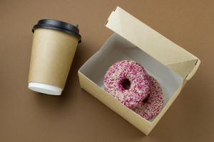 a pink donut in a box next to a cup of coffee at Hotel Alt Deutz City-Messe-Arena KONTAKTLOSER SELF CHECK-IN in Cologne